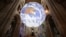 A member of the clergy poses under British artist Luke Jerram's installation 'Gaia', a 7 meter replica of planet Earth, suspended in the nave of Ely Cathedral in Ely, Cambridgeshire, on June 30, 2021.