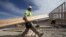 Construction worker Miguel Fonseca carries lumber as he works on a house frame for a new home, Nov. 16, 2012, in Chula Vista, Calif.