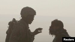 在阿富汗东部楠格哈尔省一个美军和阿富汗警方的检查哨所，一名美国士兵和一名翻译对话的侧影（资料图片)
