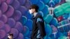 A pedestrian wears a face mask as he walks past a mural of a fish while strolling on the boardwalk at Coney Island, April 2, 2020, in the Brooklyn borough of New York.