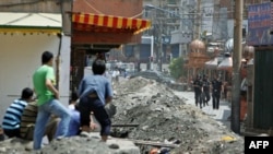 资料照：中国武警守在乌鲁木齐一处维吾尔社区的入口，几名维吾尔人注视着他们。(2019年7月8日)