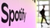 FILE - A person walks past a banner with an Spotify logo at the Frankfurt, Germany, book fair Oct. 17, 2024.
