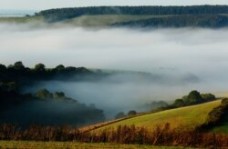 FILE - Autumn mists hang over villages and the countryside in the South Downs National Park near Amberley in Southern England.