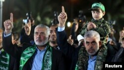 Ismaïl Haniyeh, le chef du Hamas, salue la main levée, lors de sa visite à Gaza, à côté de Yahya Al-Sinwar, chef du parti dans la ville, qui porte son fils Mazen Fuqaha sur les épaules, 27 mars 2017.