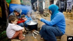 Anak-anak pengungsi Suriah dan ibunya sedang mempersiapkan makanan dekat tenda mereka di kamp pengungsi Ketermaya, Lebanon.(AP/Mohammed Zaatari) 
