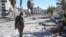 FILE - A member of the Syrian Democratic Forces (SDF) walks through a heavily damaged street leading to an Armenian church in Raqqa, Syria, Oct. 18, 2017.