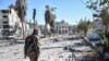 FILE - A member of the Syrian Democratic Forces (SDF) walks through a heavily damaged street leading to an Armenian church in Raqqa, Syria, Oct. 18, 2017.