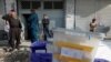 Afghan police officers stand guard while election commission workers prepare ballot boxes and election material at a polling station in Kabul, Afghanistan, Oct. 19, 2018.