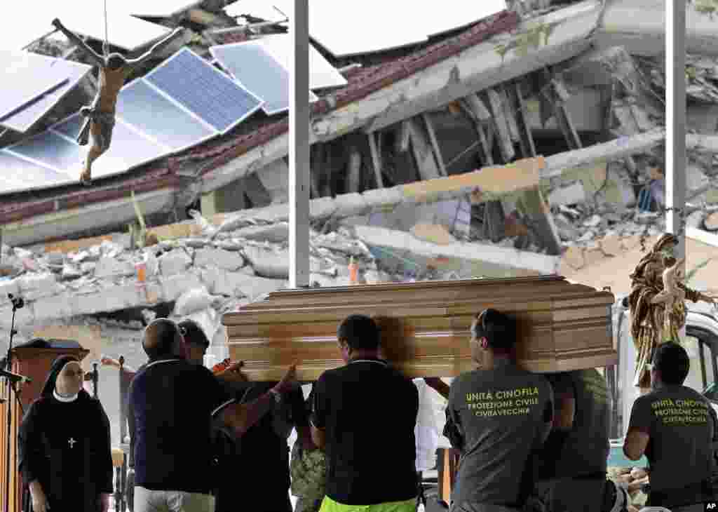 Civil Protection operators carry a casket ahead of a state funeral for some of the victims of last Wednesday's earthquake, in Amatrice, central Italy,