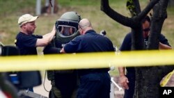 A member of the Nashville Metro Police Bomb Squad unit suits up before checking a device on the side of a movie theater following a shooting Wednesday, Aug. 5, 2015.
