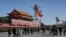 A U.S. flag is displayed beside a Chinese flag as tourists flock outside the Forbidden City in Beijing, Nov. 12, 2014. 