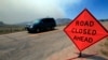一辆汽车行驶在科罗拉多州利弗莫尔附近的拉里默郡74号公路西上。路上有“前方路段关闭”标示。背后可见野火引起的浓烟。（资料照）