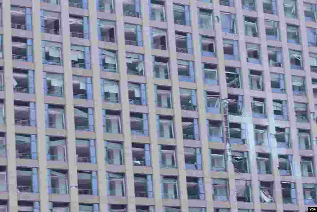 天津爆炸事故现场，核心爆炸区周围多座居民楼窗户被震碎，高速公路桥梁受损，多辆大货车被炸翻，小汽车起火或被砸，多名当地居民仍逗留在事故现场。（美国之音记者东方拍摄）