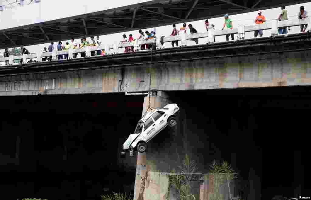Sebuah taksi tergantung di sisi jembatan selama latihan menghadapi bencana gempa bumi di seluruh kawasan metropolitan, di sepanjang jalan raya EDSA di daerah Makati, Metro Manila, Filipina.