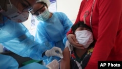 A young boy reacts as he receives a shot of the Sinovac's COVID-19 vaccine at a Samrong Krom health center outside Phnom Penh, Cambodia, Friday, Sept. 17, 2021. (AP Photo/Heng Sinith)