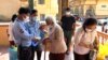 Cambodian authorities perform a temperature check on an elderly woman before entering the pagoda to celebrate Khmer New Year, Phnom Penh, Cambodia, April 14, 2020. (Hean Socheata/VOA Khmer) 