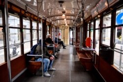 Passengers sit at distance from each others on a tram in Milan, Italy, March 12, 2020.