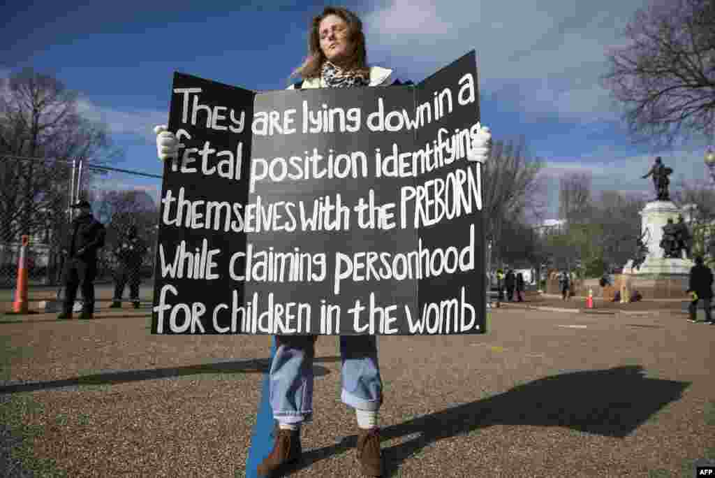 A demonstrator holds a sign during a &quot;die-in&quot; in front of the White House, Jan. 27, 2017, in Washington, D.C.