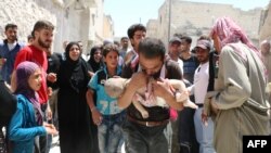 یک مردم سوری جسد کودکش را پس از آنکه از زیر آوار ساختمان های ویران شده در حملات هوایی بیرون کشده شد حمل می کند - ۳ مرداد ۱۳۹۵