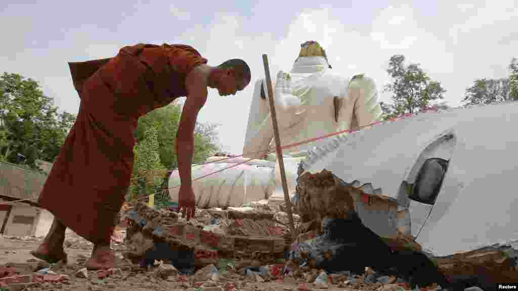 Seorang biksu Buddha memeriksa patung Buddha yang rusak akibat gempa bumi di kuil Udomwaree di Chiang Rai, Thailand utara, 6 Mei 2014.