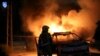 An Israeli firefighter stands near a burning Israeli police car during clashes between Israeli police and members of the country's Arab minority in the Arab-Jewish town of Lod, Israel, May 12, 2021. 