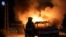 An Israeli firefighter stands near a burning Israeli police car during clashes between Israeli police and members of the country's Arab minority in the Arab-Jewish town of Lod, Israel, May 12, 2021. 