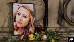 2018年10月9日，在保加利亚鲁塞的自由纪念碑举行的守夜活动期间，被杀害的电视记者维多利亚·马琳诺娃的肖像被放置在鲜花和蜡烛的旁边。