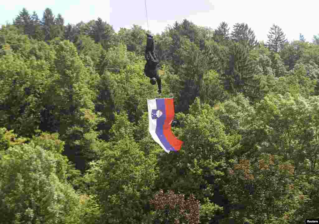 Seorang anggota Satuan Polisi Khusus memegang bendera Slovenia saat turun dari helikopter di kota Tacen, Slovenia.