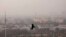 FILE - A bird flies through a thick layer of smog in New Delhi, India, Nov. 20, 2024.