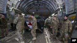 英军人员在停在法国一陆军基地的一架英国C17运输机内装载的法军医疗装甲车前走过。英美都在向法国在马里的行动提供支持。(2013年1月14日)
