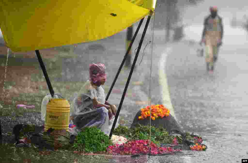 ក្មេងប្រុស​ម្នាក់រង់ចាំ​ភ្ញៀវនៅ​ក្នុង​តង់​លក់ផ្កា​ពេល​កំពុង​ភ្លៀងខ្លាំង​នៅ​ទីក្រុង Allahabad ប្រទេស​ឥណ្ឌា។