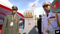 រូបឯកសារ៖ មន្ត្រី​ព្រំដែន​របស់​កម្ពុជា ​(ឆ្វេង) និង​​មន្ត្រី​ព្រំដែន​របស់​វៀតណាម​ឈរ​នៅ​ខាង​មុខ​បង្គោល​ព្រំដែន​ថ្មី​មួយ​​លើ​ទឹក​ដី​កម្ពុជា រវាង​ខេត្ត​ Gia Lai របស់​វៀតណាម និង​ខេត្ត​រតនគីរី​របស់​កម្ពុជា កាល​ពី​ថ្ងៃ​សៅរ៍ ទី​២៦ ខែធ្នូ ឆ្នាំ​២០១៥។ 