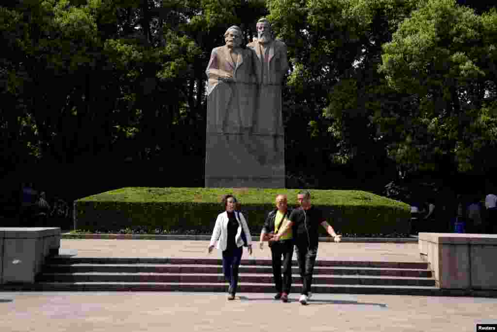2018年5月3日，中国上海的一个公园里，人们走在德国哲学家卡尔·马克思和弗里德里希·恩格斯雕像前面。