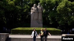 上海的一个公园里有共产主义理论家卡尔·马克思和弗里德里希·恩格斯的雕像。前面有三个人走过（2018年5月3日）。中共推崇马克思主义，限制外国学者在华研究。