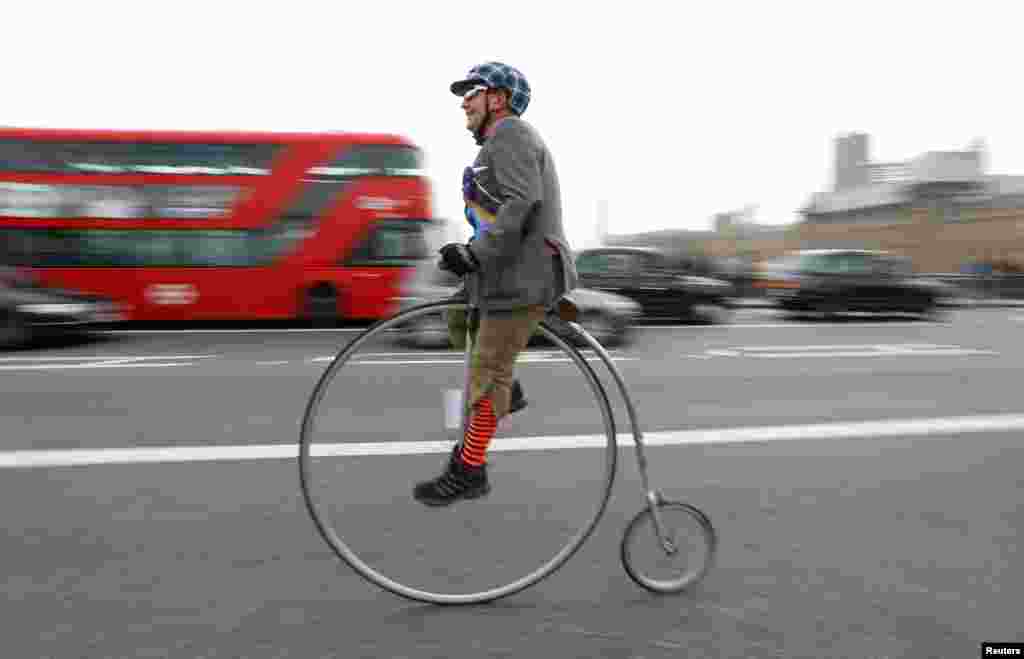 Seorang peserta acara &#39;Tweed Run&#39;, berpakaian tradisional Inggris dan mengendarai sepeda unik, melewati jembatan Westminster di London, Inggris.