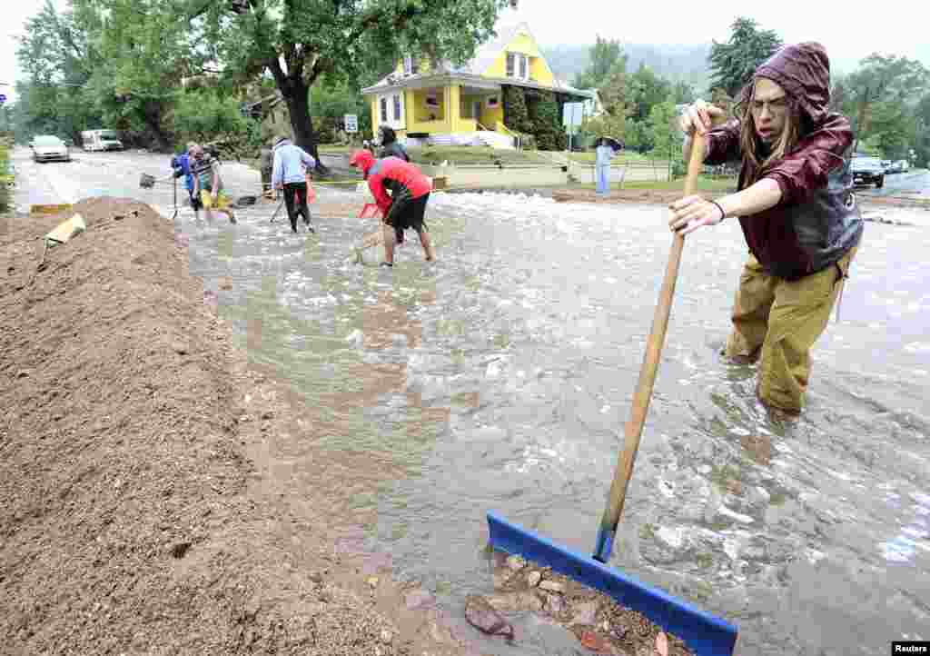 Seorang warga membersihkan jalan dari puing-puing yang diakibatkan hujan besar yang membawa banjir parah di Boulder, Colorado (12/9).