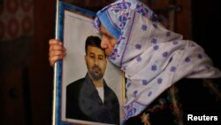 12일 가자지구 남부 칸유니스에서 석방될 예정인 팔레스타인 수감자의 어머니가 아들의 사진에 입맞추고 있다.