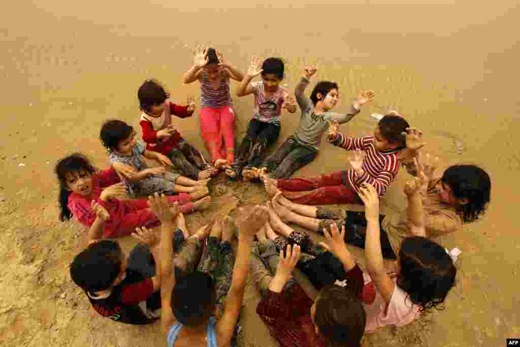 Anak-anak Palestina bermain-main di pantai di kota Gaza selama badai debu yang melanda Timur Tengah. 