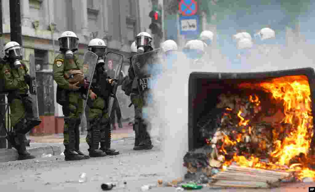 A garbage bin burns as riot police look on during clashes in front of the parliament in Athens, Greece, October 9, 2012. 