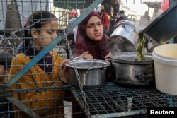 Palestinians wait to receive a free meal comprising Khobiza, a wild leafy vegetable, during the holy month of Ramadan, amid the ongoing conflict between Israel and Hamas, in Jabalia in the northern Gaza Strip, March 22, 2024. (REUTERS/Mahmoud Issa)