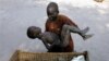 In this Dec. 21, 2005 file photo, a mother gently places her son in a basket as she takes him to a Medecins Sans Frontieres clinic after he contracted malaria, in Lankien, Southern Sudan. The fight against malaria is slowing down with a dramatic drop in t