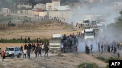 ፎቶ ፋይል፤ እ.ኤ.አ. በሜይ 18፣ 2024 ዓ.ም ፍልስጤማውያን በማዕከላዊ ጋዛ ሰርጥ ኑሴራት አቅራቢያ የርዳታ ቁሳቁስ የጫኑ መኪኖችን እየተሯሯጡ ሲከተሉ። 