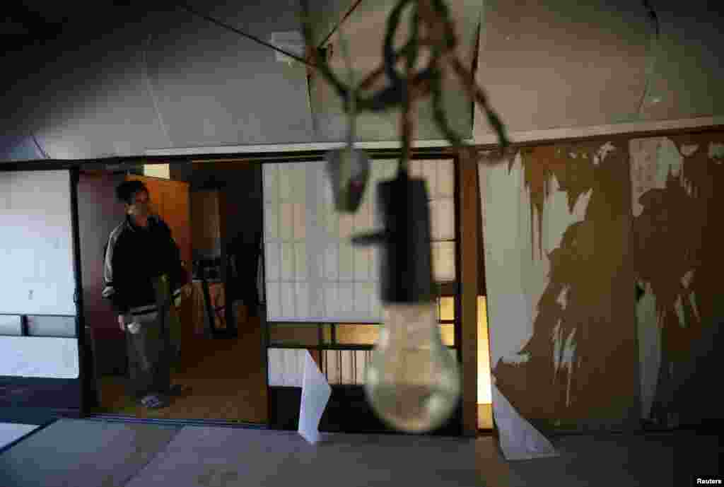 Toshio Koyama, yang dievakuasi dari Miyakoji tiga tahun lalu, melihat pabrik ulat sutra yang rusak dekat ruamhnya saat ia kembali ke rumah bersama istrinya Kimiko, di Tamura, prefektur Fukushima (1/4).