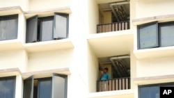 A foreign worker talks on the phone outside his room at the WestLite Toh Guan dormitory after it was declared an isolation area under the Infectious Diseases Act, following a spike in the number of COVID-19 cases in several foreign worker dormitories.