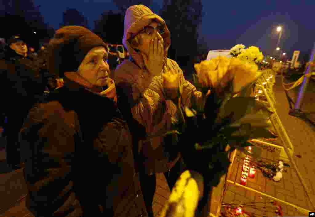 Orang-orang menaruh bunga dan menyalakan lilin di depan supermarket Maxima di Riga, Latvia. Banyak warga sedang mencari makanan setelah pulang kerja di ibukota Latvia itu ketika sebagian besar dari atap supermarket itu runtuh.
