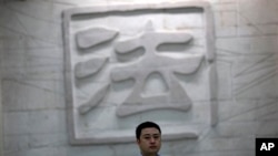 一名男子走过中国一家法院刻有“法”字的墙壁。（资料照片）