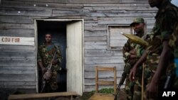 Para pejuang pemberontak M23 berdiri di luar rumah kayu di desa Kanyarucinya, 6 kilometer dari Goma, di wilayah timur Republik Demokratik Kongo (DRC) (18/11).