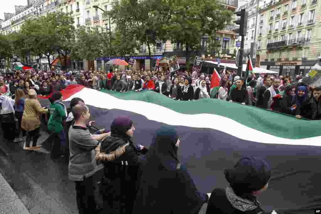 Pengunjung rasa pro-Palestina membawa bendera raksasa dan menyerukan teriakan anti Israel ketika protes menentang serangan udara Israel di jalur Gaza, Paris, 13 Juli 2014.