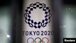 FILE - The logo of Tokyo 2020 Olympic Games, that have been postponed to 2021 due to the coronavirus outbreak, is seen through signboards, at Tokyo Metropolitan Government Office building in Tokyo, Japan, Jan. 22, 2021. 