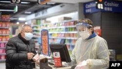 Wasu ma'aikata a wani shagon sayar da kayayyaki a yankin Wuhan da tutar coronavirus ta fara bulla a China